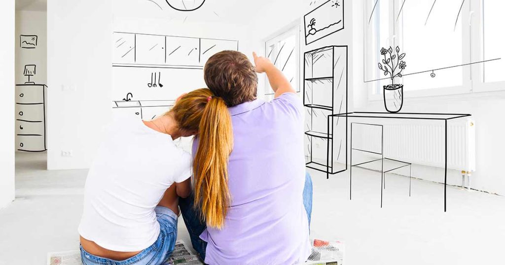 A couple sits in an empty room, imagining home decor; black line drawings of furniture and decorations are sketched onto the white walls, visualizing their future interior design.